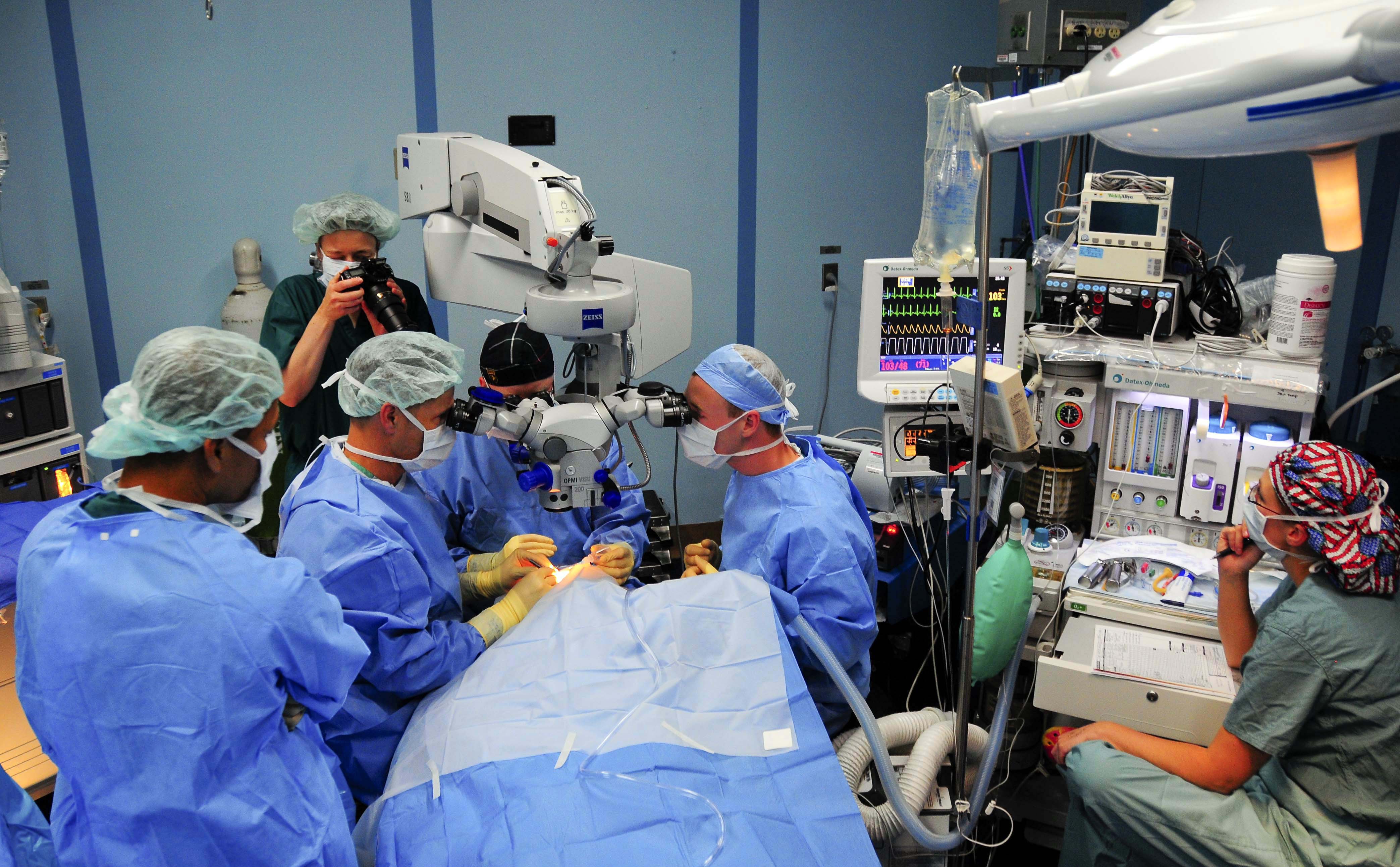 Operating room team performing ophthalmic surgery under a microscope