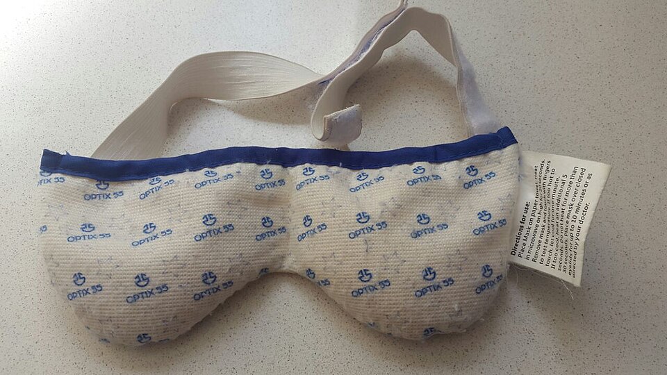 Microwavable warm compress mask used for eyelid therapy resting on a countertop.