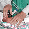 Physician performing bedside indirect ophthalmoscopy on a premature infant
