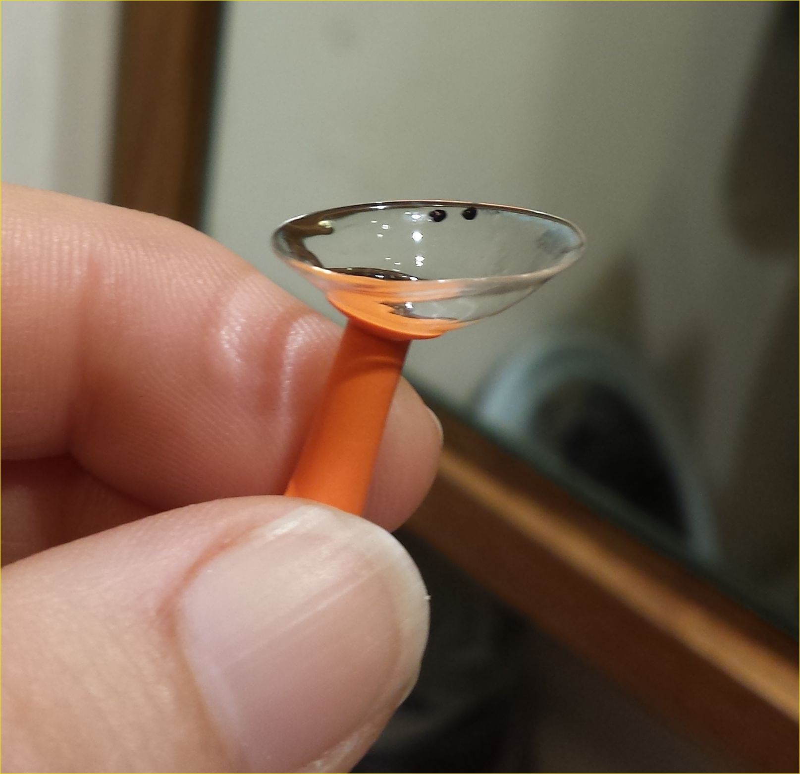 Scleral lens balanced on an orange insertion plunger