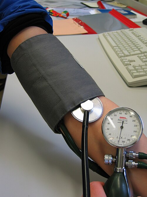 Healthcare worker checking a patient’s blood pressure with a manual cuff.