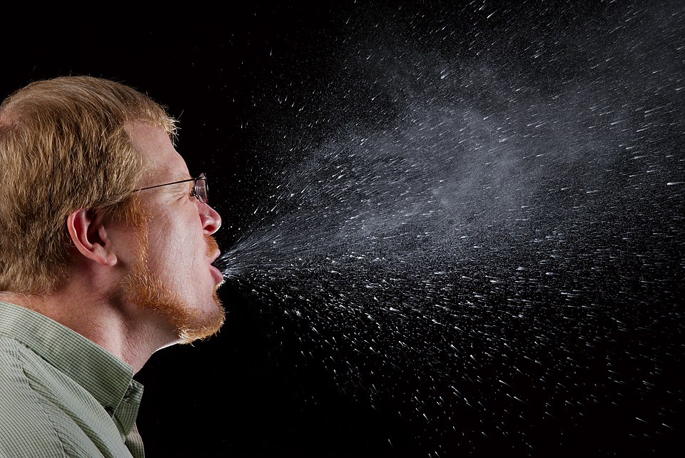 High-speed photograph capturing a sneeze with airborne droplets.