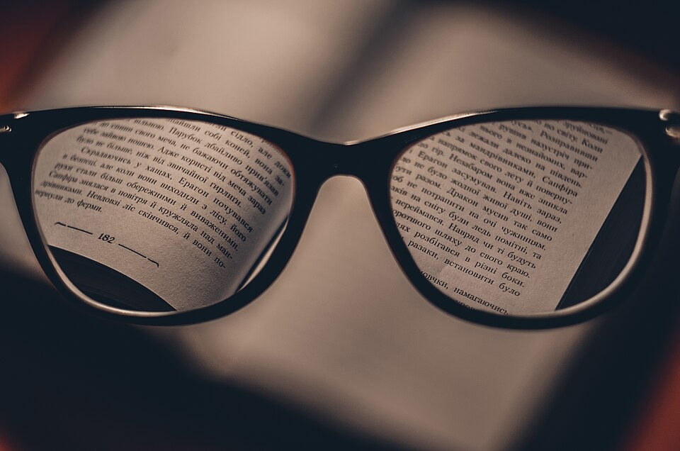 Book text seen sharply through a pair of reading glasses
